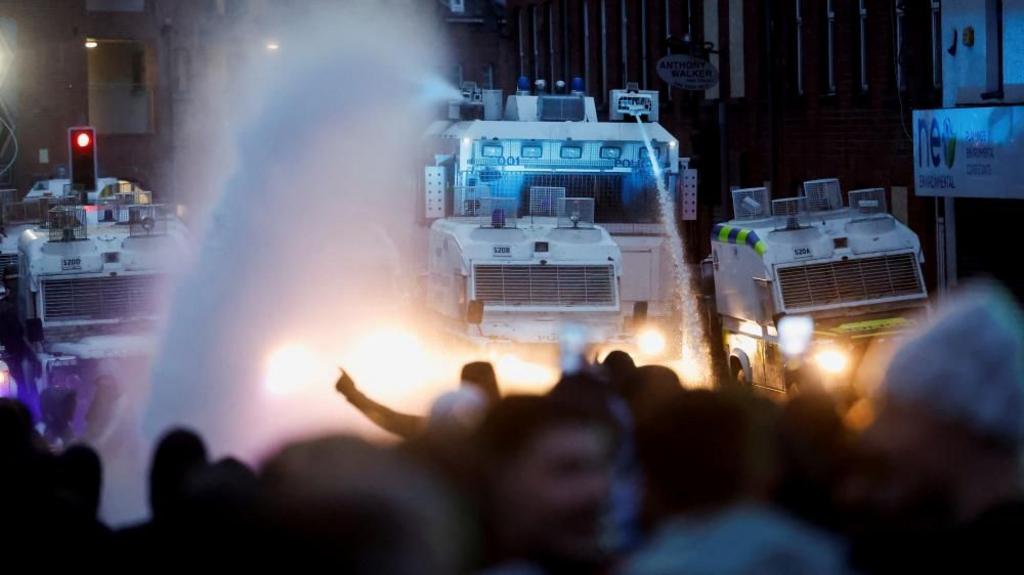 Police aim a water cannon at demonstrators as riots continue in Ballymena, Northern Ireland, June 11, 2025