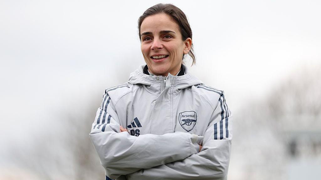 Renee Slegers smiles while standing with her arms crossed