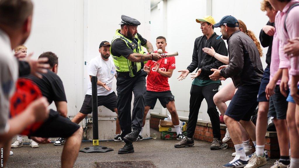 A police officer playing cricket