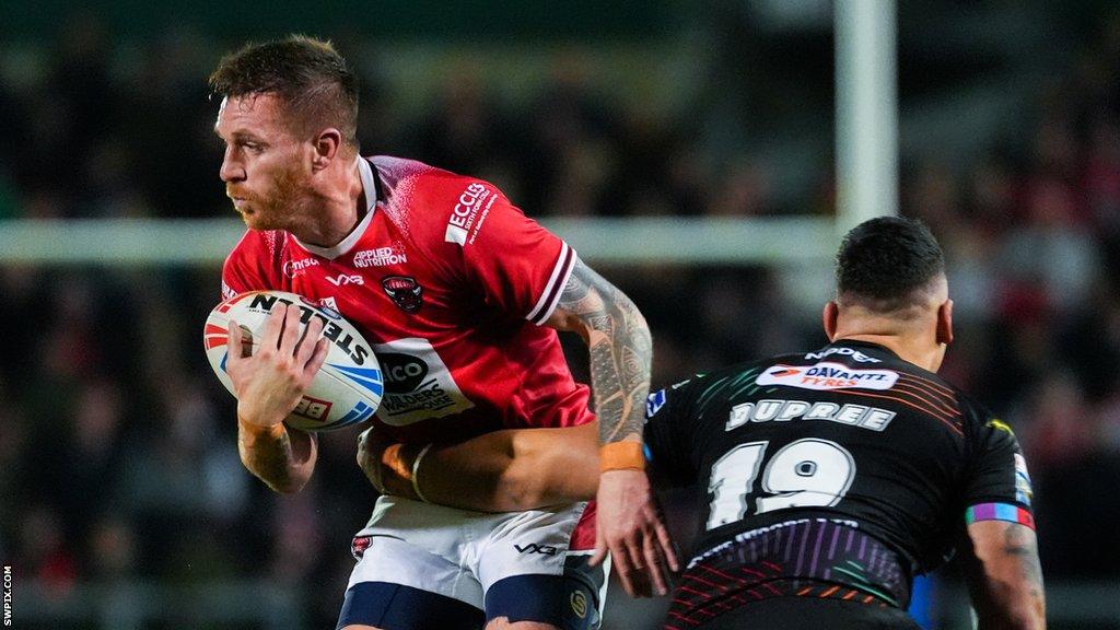 Salford's Marc Sneyd being tackled by Tyler Dupree of Wigan