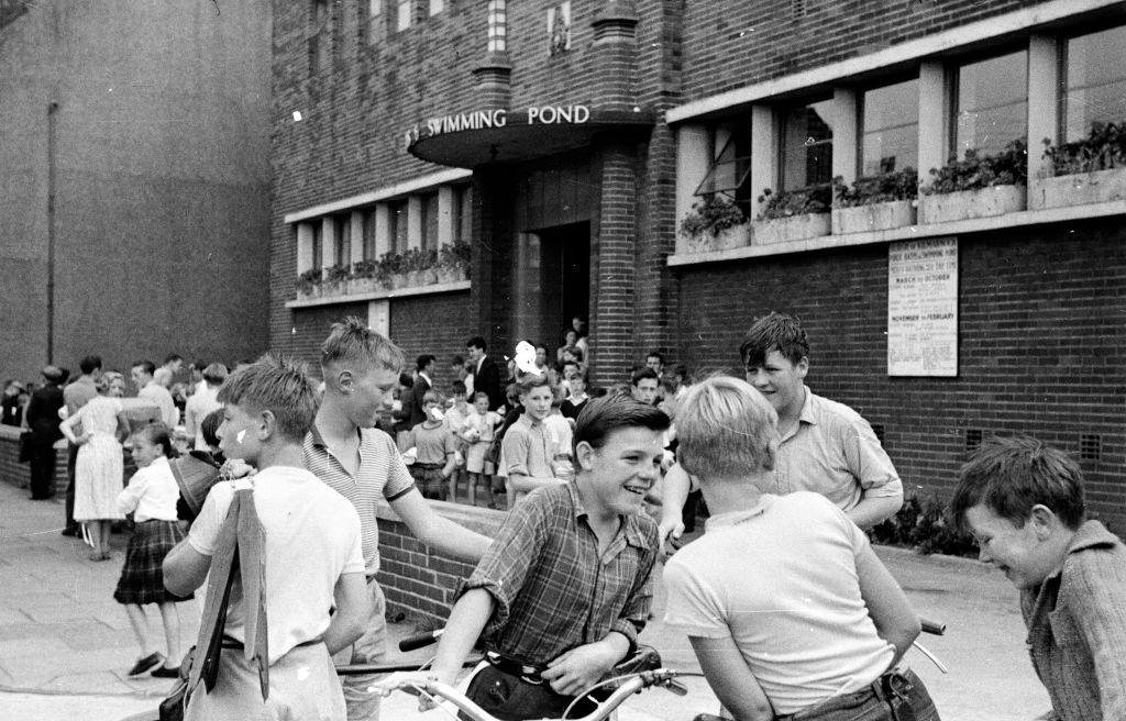  happy crowd of children streaming in and out of a public swimming pool in the Scottish industrial town of Kilmarnock. 