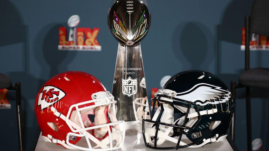 A Kansas City Chiefs helmet, the Vince Lombardi Trophy and a Philadelphia Eagles helmet.