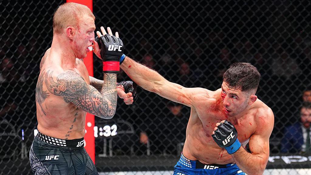 Mason Jones is punched by Axel Sola, both men bloodied in their fight