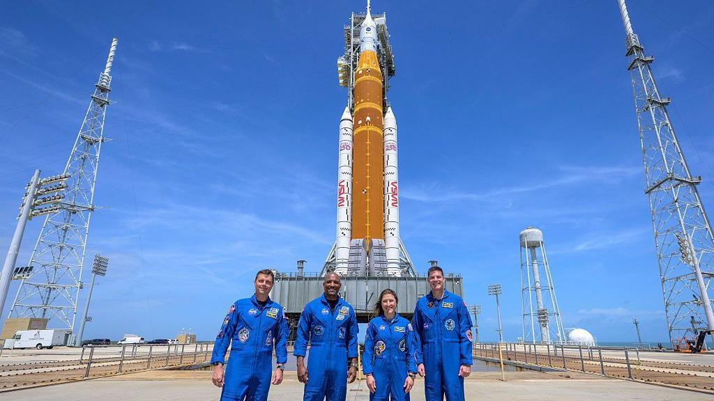 Four astronauts in front of the SLS rocket.