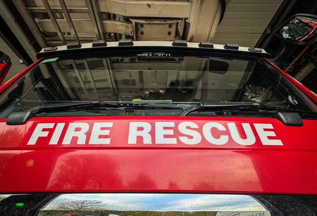 A fire engine with 'fire rescue' written on the front with red paint in the background