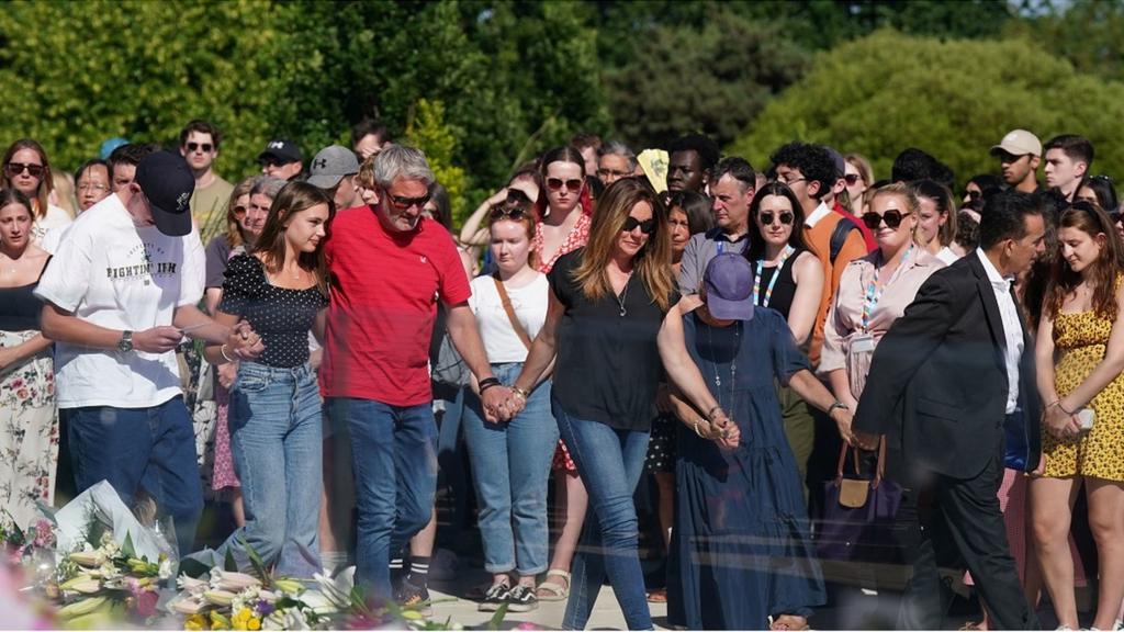 The families of the two victims link hands at the vigil