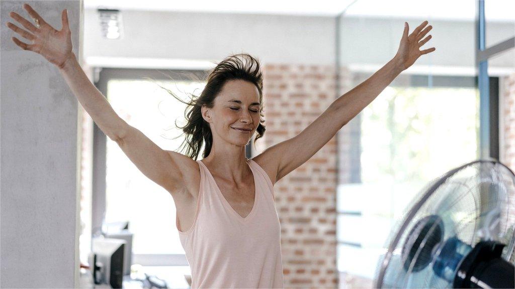 Businesswoman in office enjoying breeze from a fan - stock photo