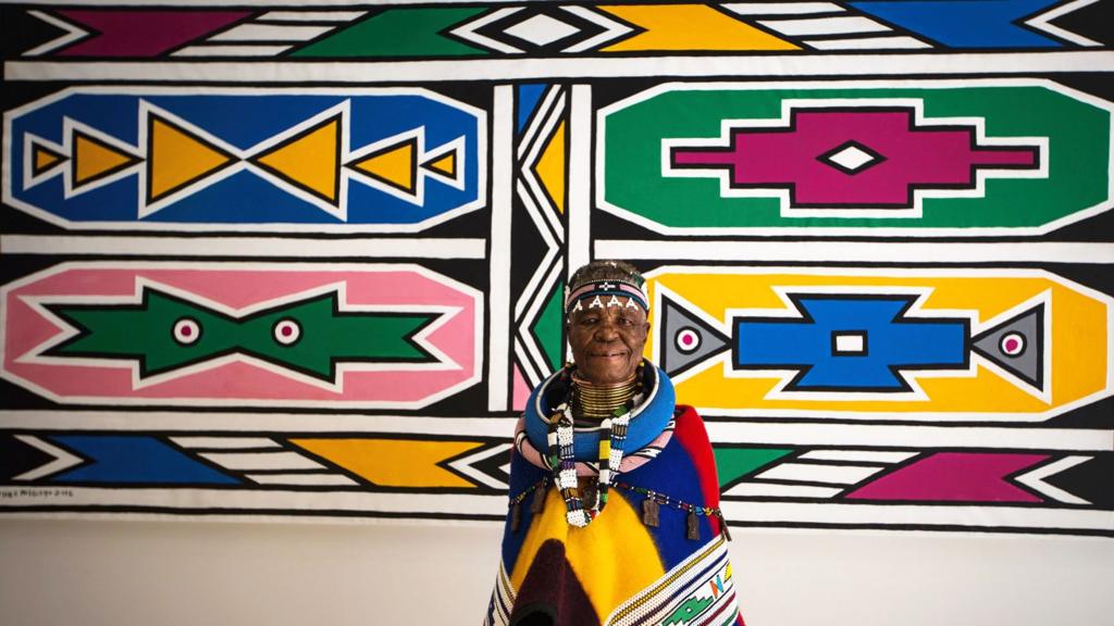 South African artist Esther Mahlangu poses in front of her artwork in March 2017 at a gallery in Johannesburg