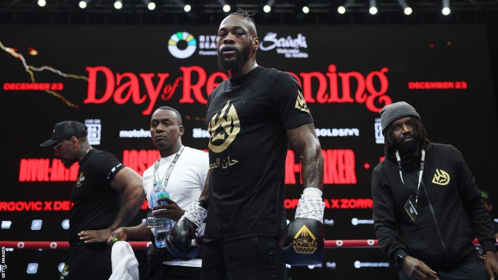 Deontay Wilders stands tall in his workout gear and gloves