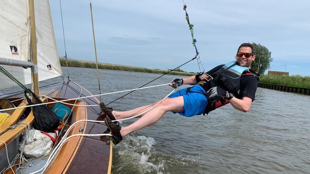 Ben hanging from the side of the boat in a harness