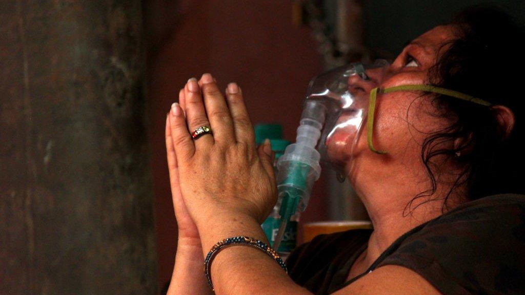 A woman with an oxygen mask on prays