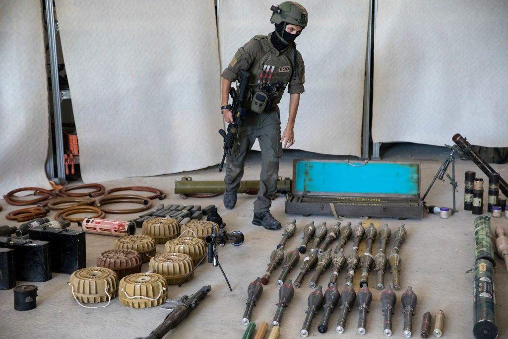 An Israeli soldier stands with grenades, rocket launchers and other military equipment and ammunition that Hamas and Palestinans militants used in their attack on Israel