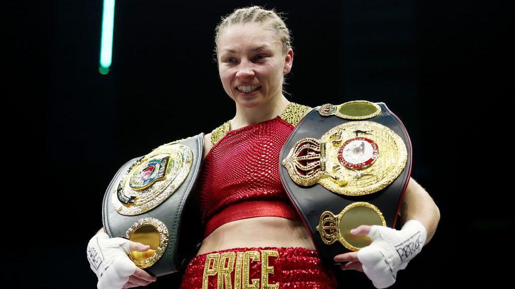 Lauren Price poses for photo with her world title belts after victory