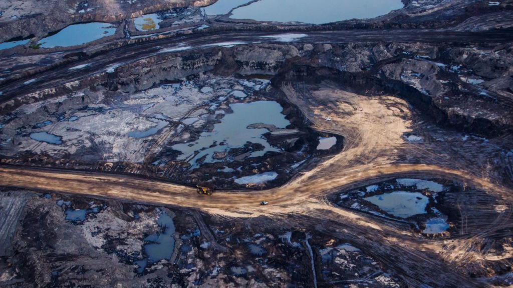 An aerial view of Athabasca oil sands near Fort McMurray, Alberta showing open deposits of oil bitumen along mining service roads.