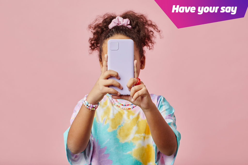 Girl holding up phone with a pink background