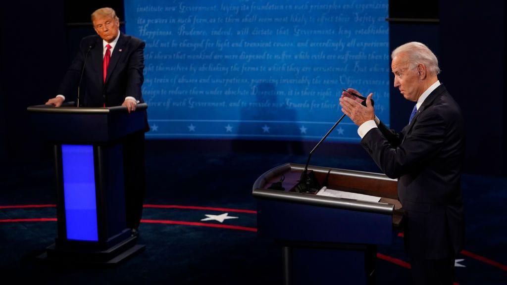 Joe Biden answers a question as Donald Trump listens during their last presidential debate