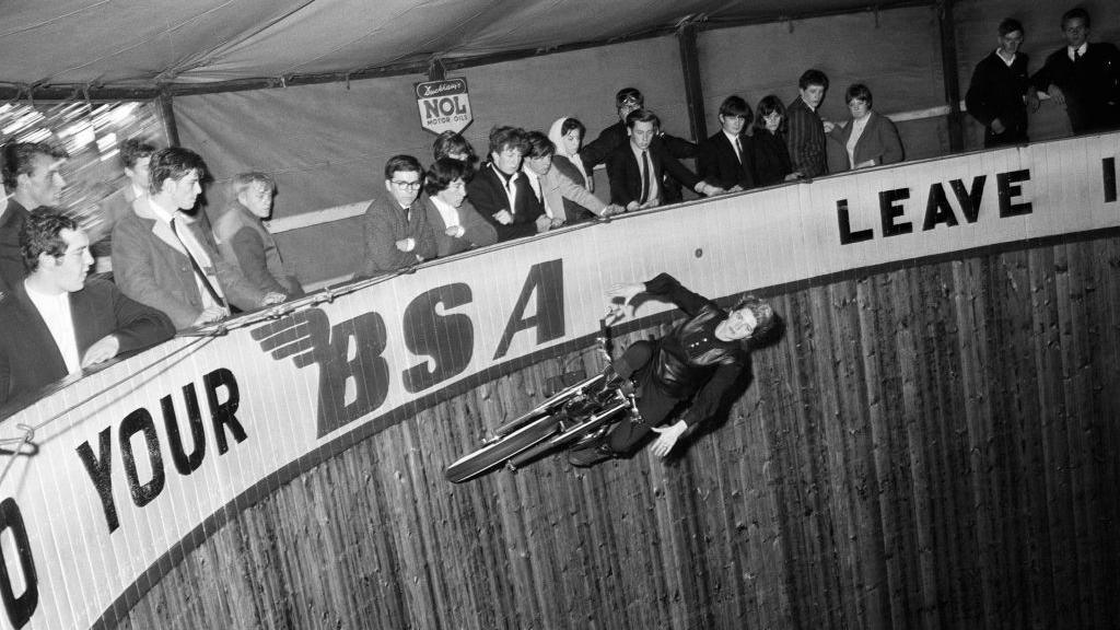 Yvonne Stage rides the "Wall of Death' at Southend Kursaal, part of the Tornado Smith troupe on 26 September, 1965. She can be seen riding the motorcycle around the edge of the cylinder as visitors watch on from the sides above. 