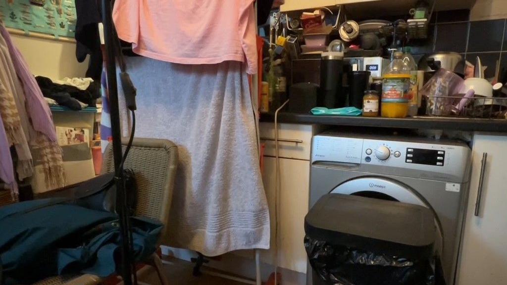 An image of Karen's kitchen which is small and piled high with her belongings. Her washing is hanging next to the kitchen bin. 