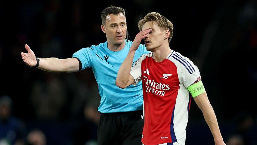 Martin Odegaard walking past the referee during Arsenal's defeat to Paris St-Germain
