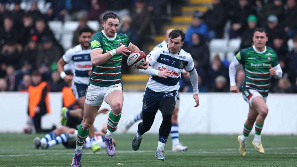 rugby player runs away from defenders with ball in hand