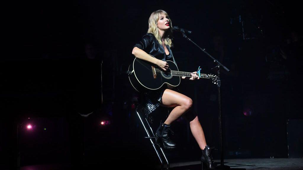 taylor swift on stage with a guitar