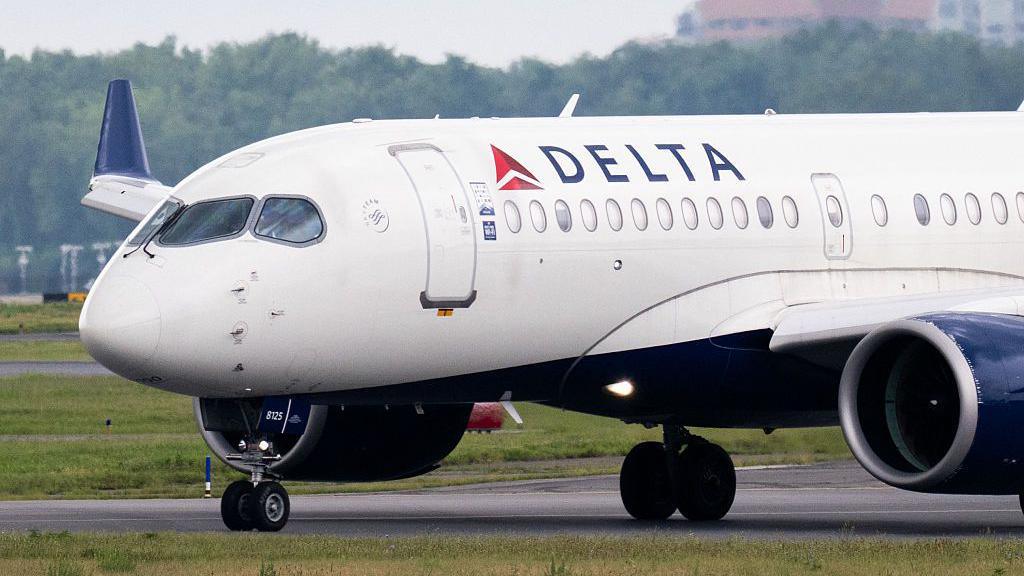 A close-up photo showing a Delta Airlines plane landing on a tarmac in Arlington, Virginia.