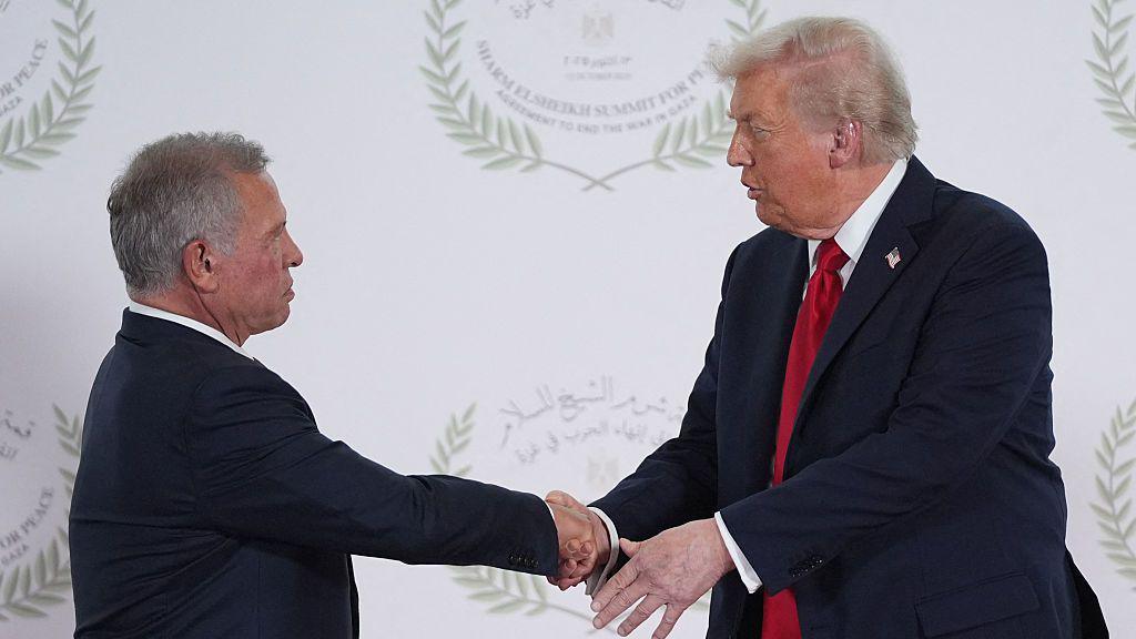 King Abdullah and Donald Trump shake hands at a peace summit in Shark el-Sheikh, Egypt. The two are wearing dark suits.