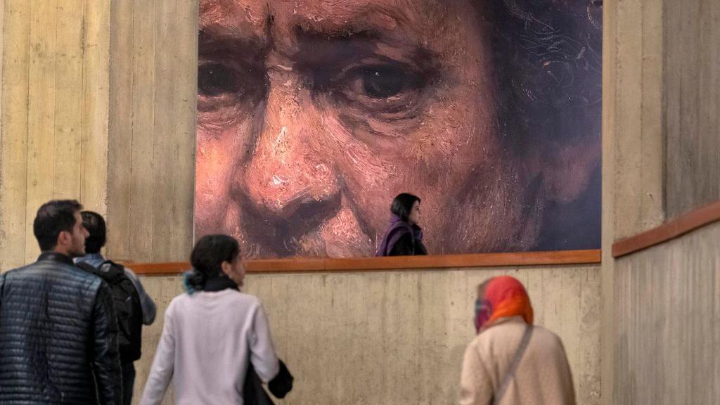 Young Iranian people walk under a copy of a detail of a self-portrait by Rembrandt (1659), the Dutch painter and printmaker, while visiting the ''Eye to Eye, Portraiture in Modern and Contemporary Art'' exhibition