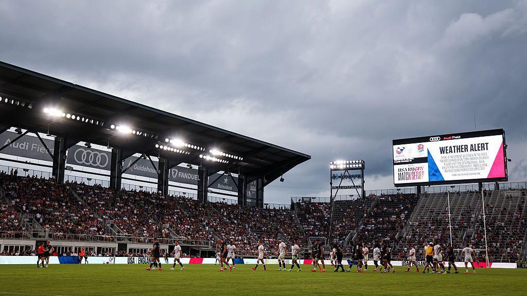 Teams walk to the locker rooms after an inclement weather alert is called during the first half of the match between the United States and England at Audi Field on July 19, 2025 in Washington, DC. 