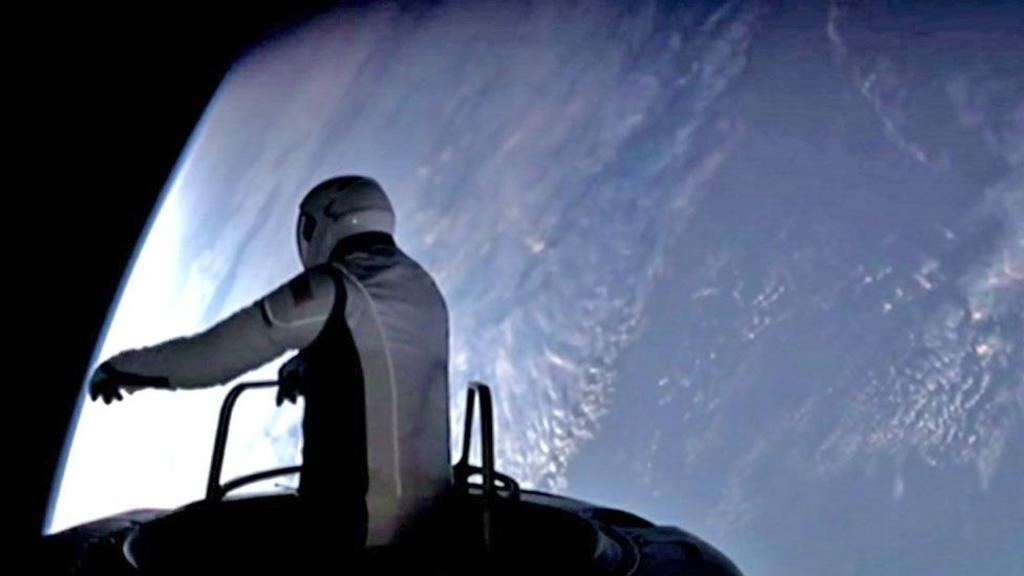 Astronaut Isaacman emerges from the capsule, silhouetted against the Earth