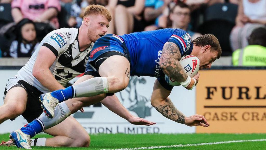 Wakefield Trinity's Tom Johnstone crashing over to score under pressure from Hull FC's Harvey Barron.