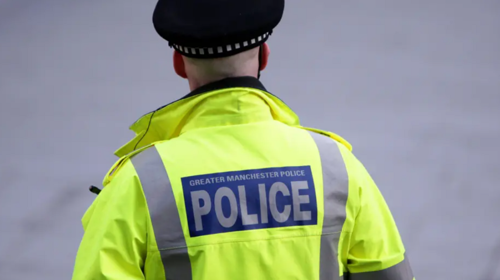 The back of a policeman wearing a light green police jacket