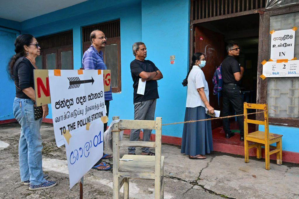 People queue at a polling station before casting their ballots to vote in Sri Lanka's parliamentary election in Colombo