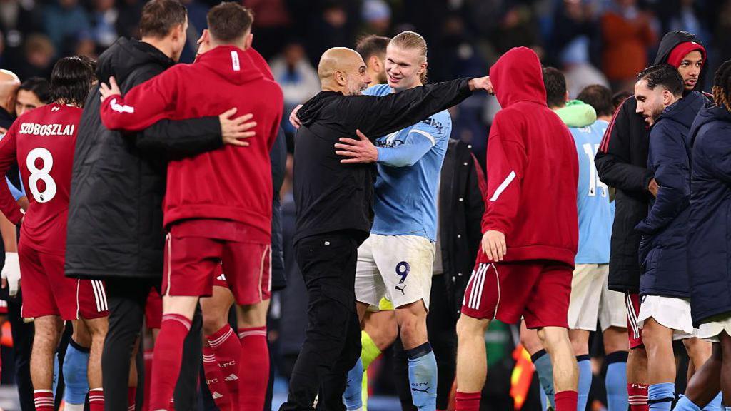 Pep Guardiola embracing Erling Haaland after the win over Liverpool, with the pair surrounded by other players from both teams