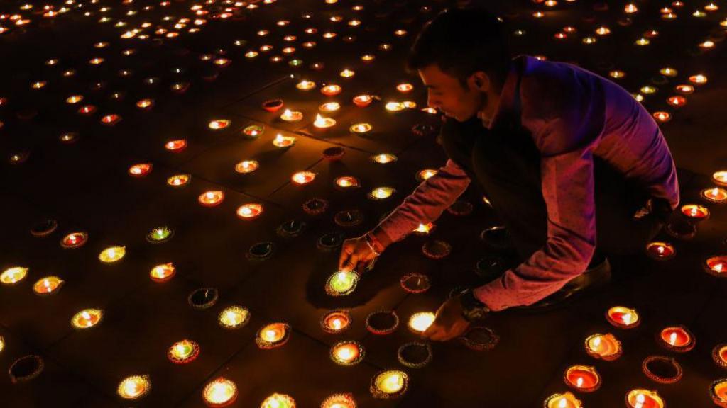 man lighting candles for diwali