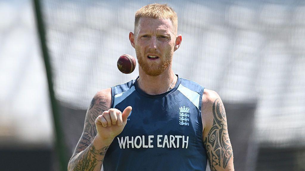 Ben Stokes, wearing a blue England vest, tosses a ball in the air