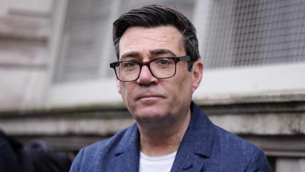 Andy Burnham in a dark grey blazer looks into the camera