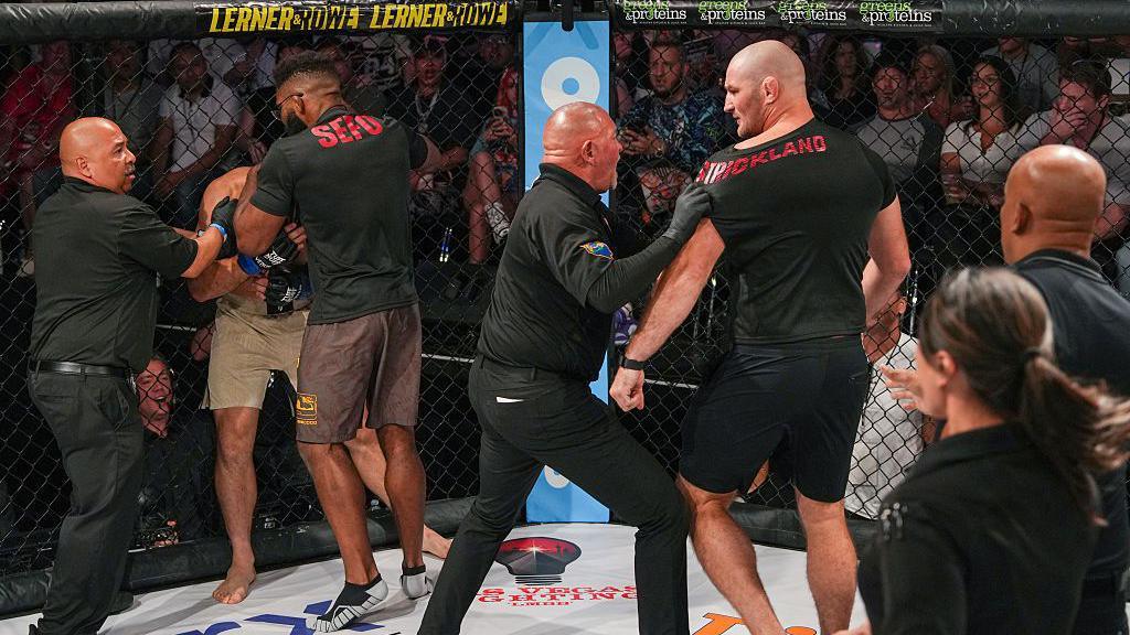 Sean Strickland is grabbed by security in the cage