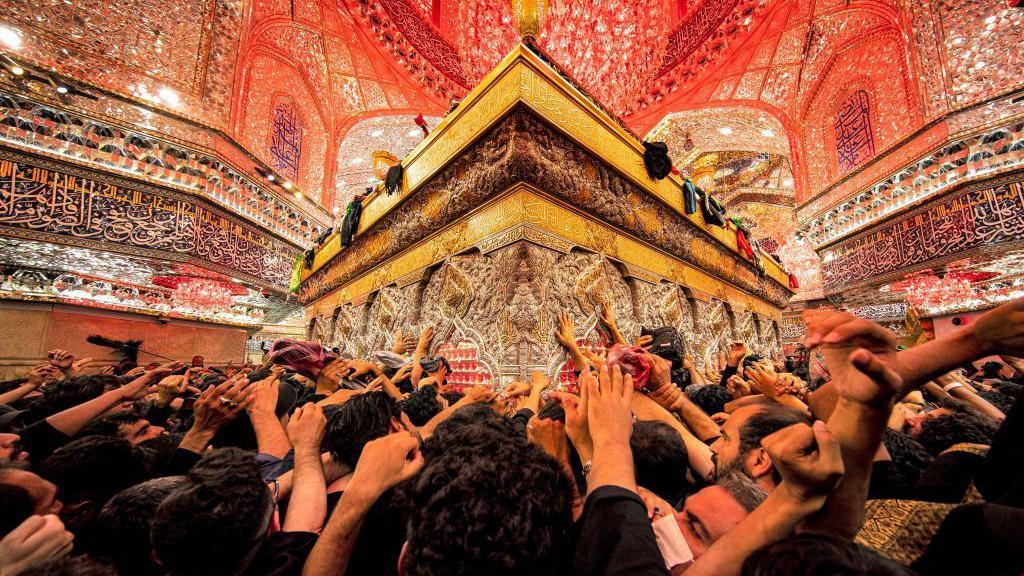 Shia Muslim devotees reach to receive a blessing from the tomb of Imam Hussein, the Prophet Mohammed's grandson, at the Imam's shrine in Iraq's central holy city of Karbala on September 6, 2023, during the Arbaeen religious festival commemorating his seventh century killing