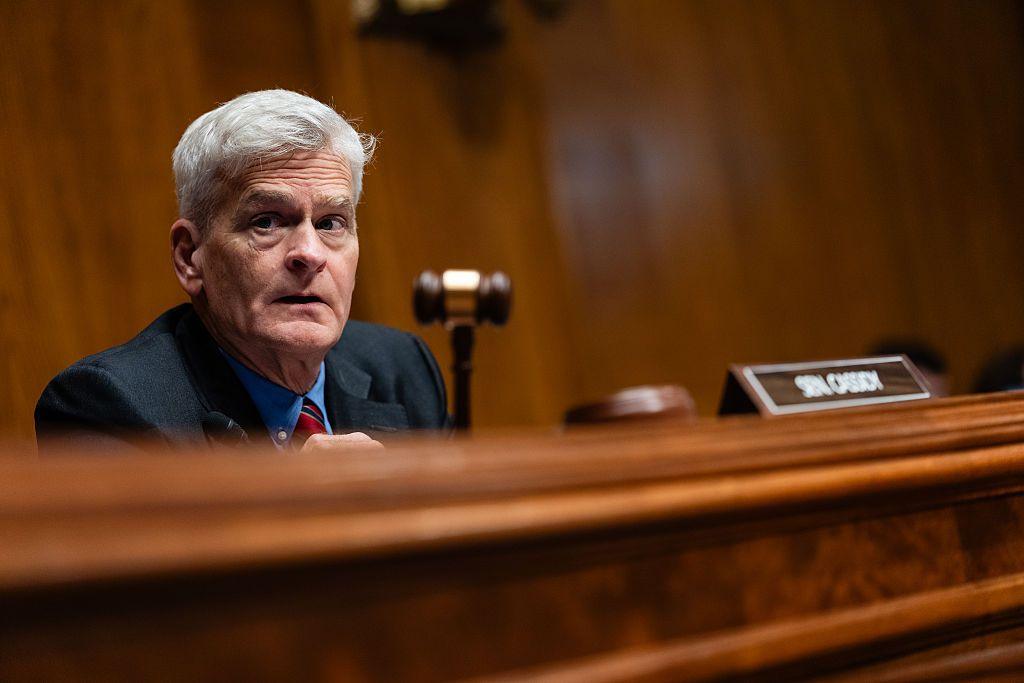 Bill Cassidy, who has grey hair and a blue shirt with a red tie, holds a gavel during a hearing on Capitol Hill.