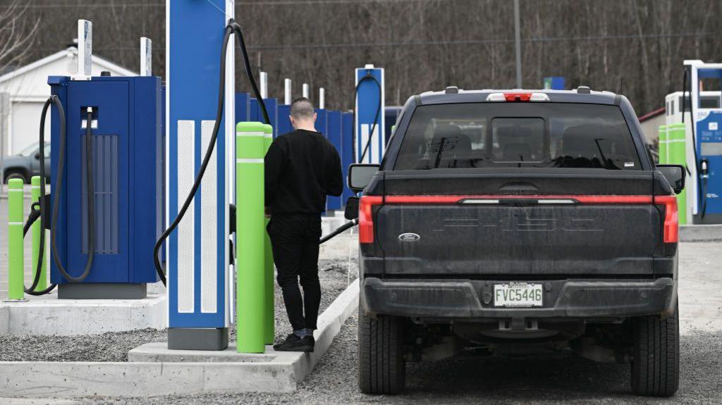 A driver charges a Ford F-150 electric pickup truck 