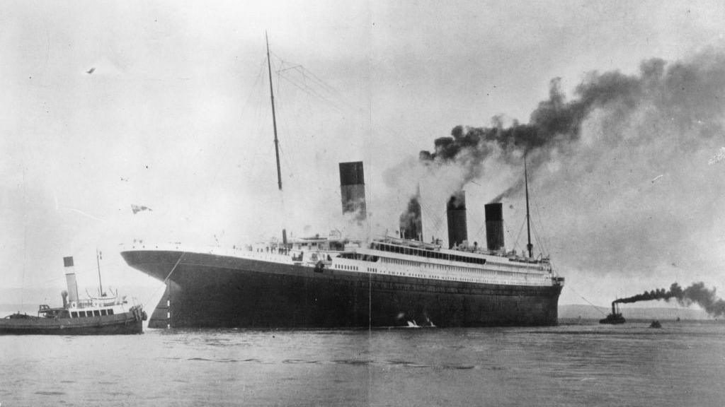 A black and white photograph of RMS Titanic on the water.