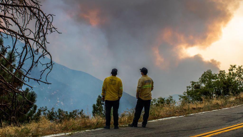 Firefighters watch the smoke as the Line Fire burns in the foothills of the San Bernardino Mountains