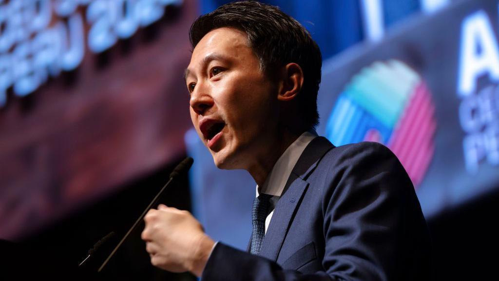 Shou Zi Chew wearing a sharp suit with short hair speaking at an event.