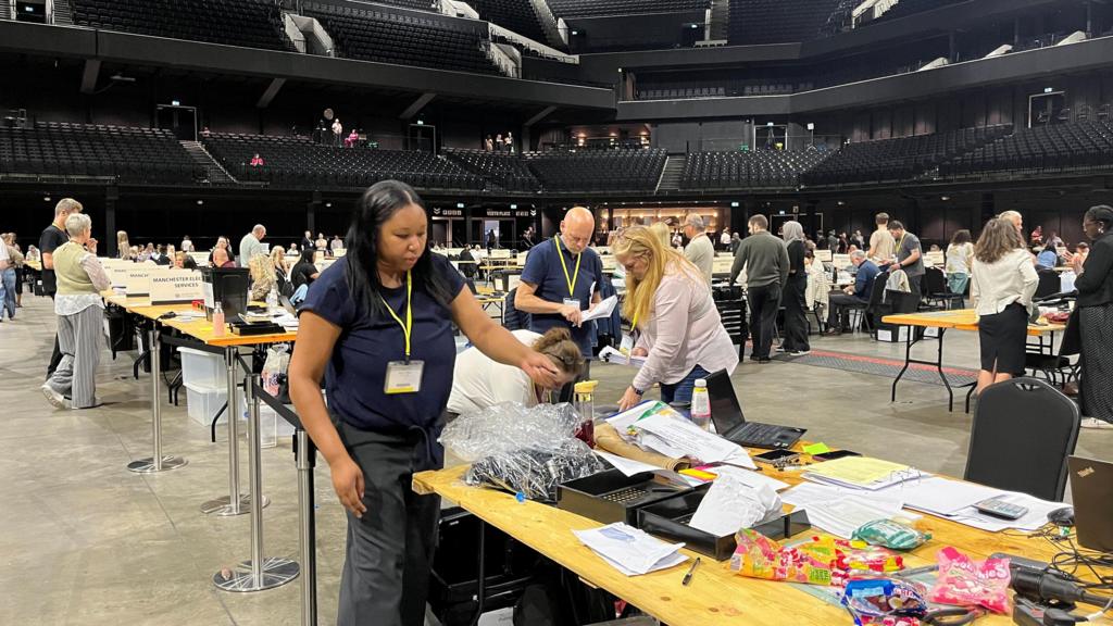 People preparing for the count in an indoor stadium.