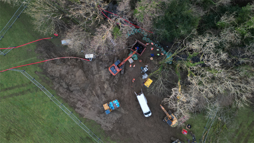 Aerial view of men in orange jackets working on a burst pipe