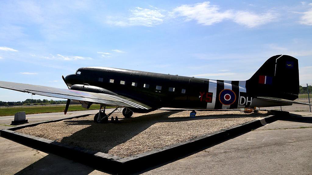 A side view of the restored Dakota Gate Guardian at RAF Brize Norton 47 Air Despatch Royal Logistic Corps in Oxfordshire on a sunny day.