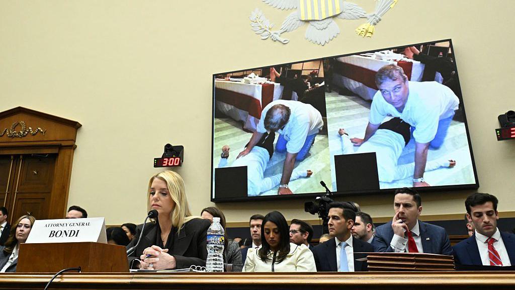 Congressman Thomas Massie speaking at a podium during a congressional hearing, with US Attorney General Pam Bondi visible in the background.
