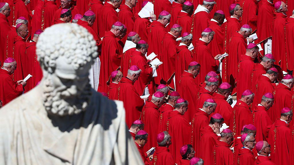 Saint Peter's statue appears in the foreground. Dozens of cardinals, wearing red, are seen during the funeral ceremony of Pope Francis at Saint Peter's Square in Vatican on April 26, 2025.