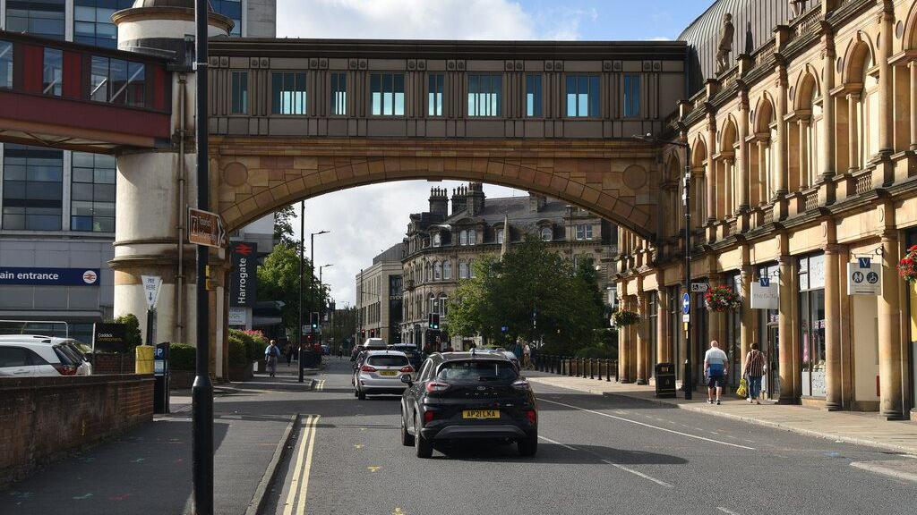 Cars drive under an archway near a station entrance.